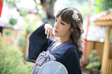Fototapeta na wymiar Beautiful young woman with dark blue Chinese lolita dress with Chinese garden