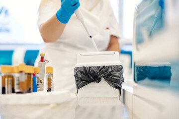 Medical waste in lab. A nurse taking care of medical waste after blood analysis. It's important to...