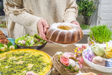 Festive dinner, Easter brunch. Traditional Easter dishes on family home table - baked meat, quiche, spring salad, muffin, colored eggs, hot cross buns