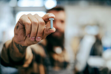 Close up of worker holding screw. Selective focus on fingers with a screw. Worker's tool. Worker in...