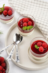 Italian dairy dessert panna cotta with raspberry jam and fresh raspberries on concrete tray