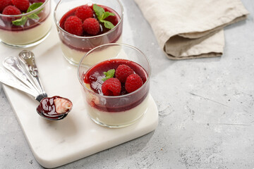 Italian dairy dessert panna cotta with raspberry jam, fresh raspberries and mint on marble board
