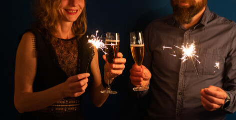 couple holding sparkles and champagne glasses Happy New Year