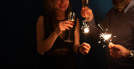 couple holding sparkles and champagne glasses Happy New Year
