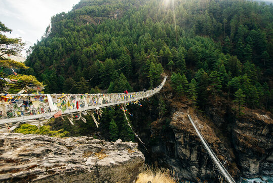 Suspension bridge with buddhist prayer flags on Himalayas in Nepal.