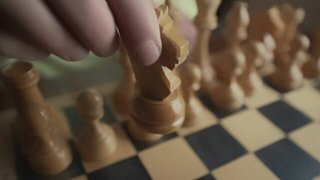 Senior mature man holding knight chess piece in hand and making move. Business strategy and home entertainment concept.