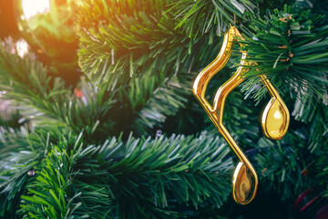 Shiny treble clef ornament or gold music notes hanging on pine tree. Stylish christmas decorations....
