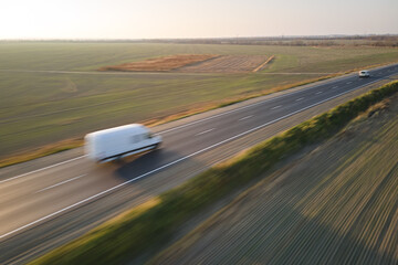 Aerial view of blurred fast moving cargo van driving on highway hauling goods. Delivery transportation and logistics concept
