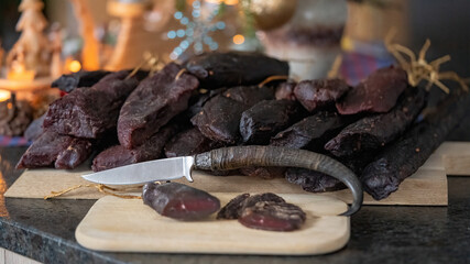 delicious ham of a chamois buck on the wood board with a hunting knife and a christmas decoration in the background