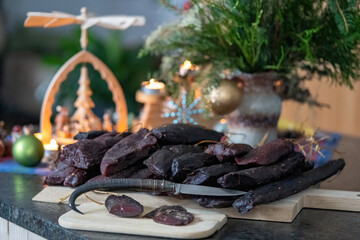 delicious ham of a chamois buck on the wood board with a hunting knife and a christmas decoration in the background