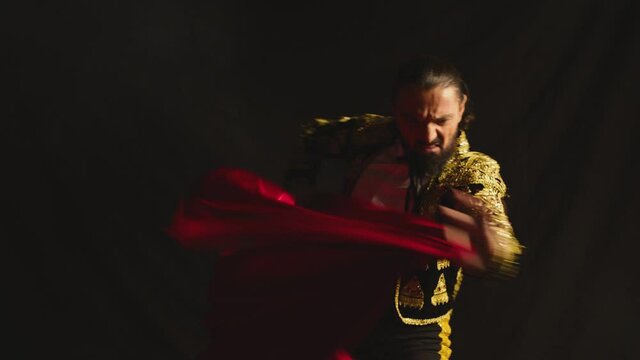 Male dancer or toreador imitating moves of matador bullfighter on black smoky background .  Man bullfighter dressed in bullfighting costume . Shot on ARRI Alexa cinema camera in Slow Motion 