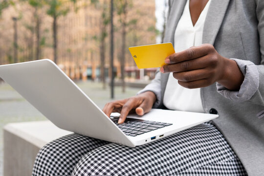Crop African American businesswoman paying with credit card using laptop