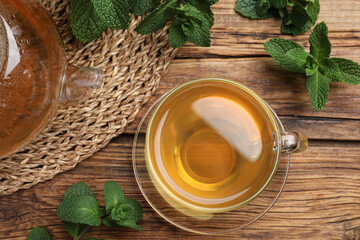 Obraz na płótnie Canvas Cup of hot aromatic mint tea on wooden table, flat lay