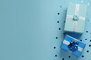 Gift boxes and shiny confetti on light blue background, flat lay. Space for text