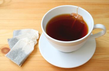 A cup of hot tea with teabags on wooden table
