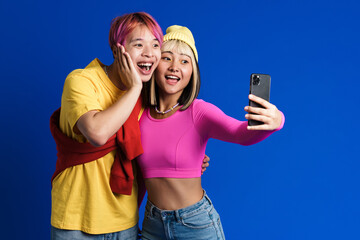 Asian teenagers laughing while taking selfie photo on cellphone