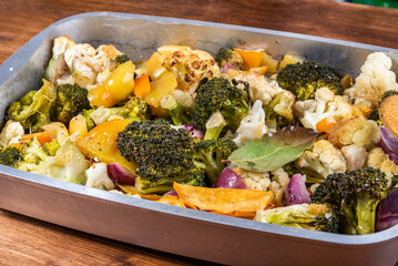 Ready-made vegetable stew of cauliflower, broccoli, tomatoes, onions and bell peppers in a baking sheet, close-up