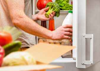 a man unpacks a box of groceries and puts them in the refrigerator