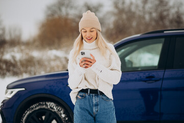 Woman using phone outside her car in a winter park