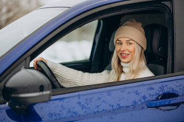 Woman sitting in her new car in a winter park