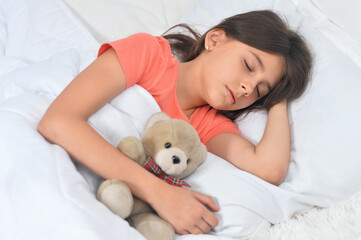 Cute little girl sleeping in bed with teddy bear