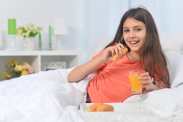 Obraz na płótnie Canvas Cute girl with breakfast at home on bed