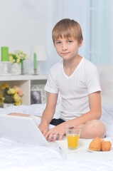 portrait of boy with laptop on bed in the morning