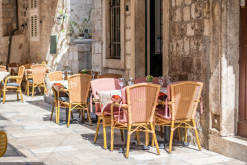 Table and chairs at the restaurant in narrow street are prepared for guests and tourist. Old city of Dubrovnik, Croatia. - obrazy, fototapety, plakaty
