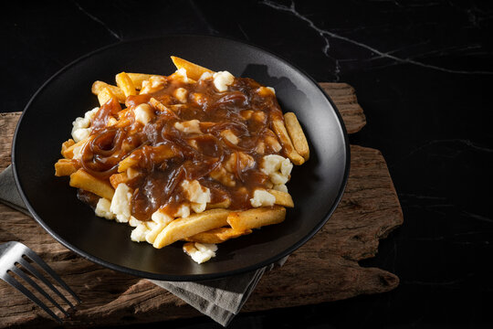 Delicious poutine with fresh cheese curd and gravy melted cheese into perfection on white background