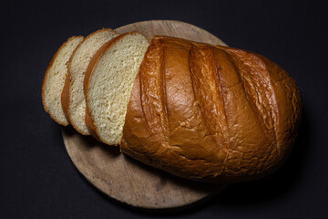 Sliced bread on a black background. Bakery product. Freshly baked loaf