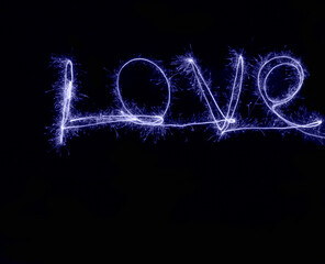 freezelight. painting at night with light using sparklers at long exposure. Love lettering. Valentine's Day. Declaration of love in the color of 2022 very peri, against a dark background.