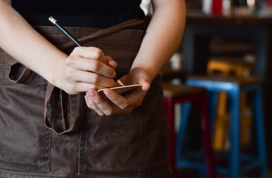 Server writing down customer order in notebook