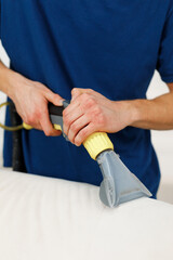 Worker from a cleaning company worker vacuuming a pillow on a white sofa