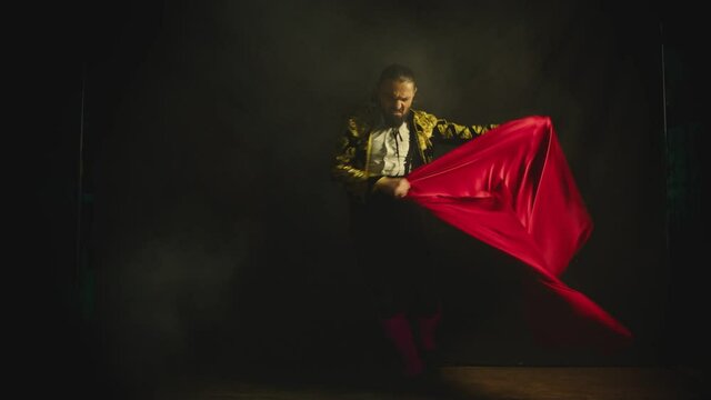 Male dancer or toreador imitating moves of matador bullfighter on black smoky background .  Man bullfighter dressed in bullfighting costume . Shot on ARRI Alexa cinema camera in Slow Motion 