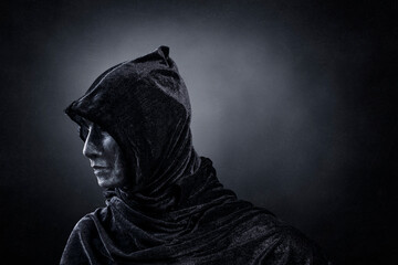 Scary figure with hooded cloak in the dark