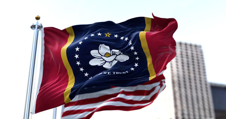 the flag of the US state of Mississippi waving in the wind with the American flag blurred in the...
