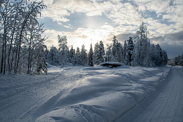 Eine eingeschneite Hütte an einem Weg in der Abendsonne in Muonio Lappland Finnland