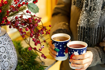 two cups of mulled wine in womans hands outside. Mulled wine with slice of orange and spices....