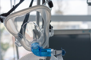 Non-invasive ventilation face mask, close up view, on background medical ventilator in ICU in...