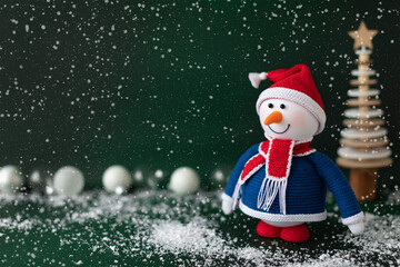 Christmas snowman in red hat and scarf standing in snow on dark green background. New year greeting...