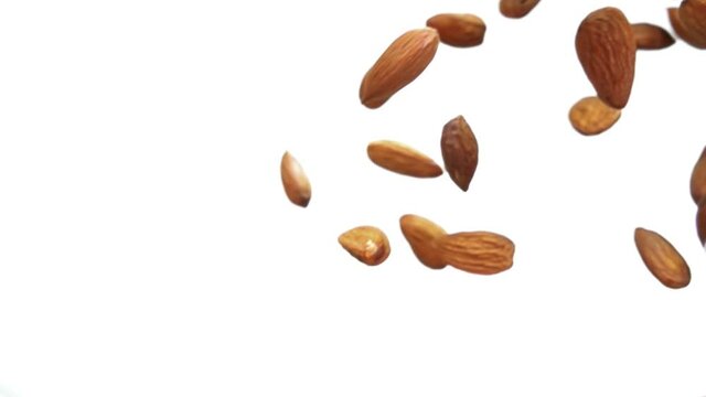 Close-up of delicious almonds falling diagonally on a white background