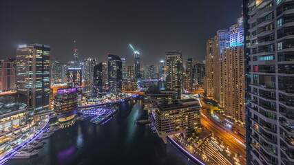 Aerial view to Dubai marina skyscrapers around canal with floating boats night timelapse