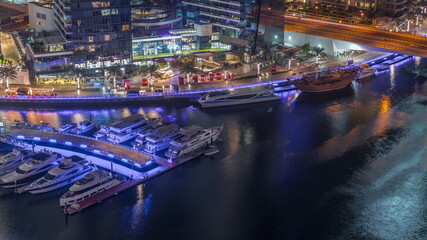 Obraz premium Dubai marina promenade on waterfront along canal aerial night timelapse.