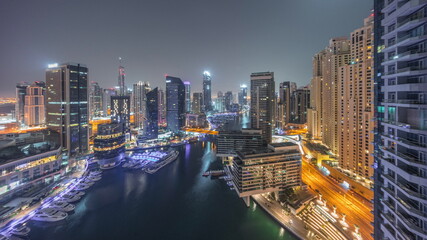 Fototapeta na wymiar Aerial view to Dubai marina skyscrapers around canal with floating boats night to day timelapse