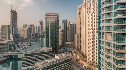 Fototapeta premium Aerial view to Dubai marina skyscrapers around canal with floating boats timelapse