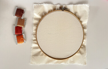  Wooden embroidery hoop with clean white fabric and earth tones threads © zimmer