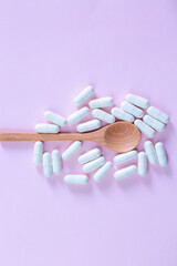 Collagen powder in wooden spoon, supplement with capsule, healthy and anti age concept on pink background, top view, copy space