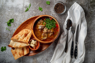 Beef goulage with garlic and pita bread and cutlery on a gray stone table - obrazy, fototapety, plakaty
