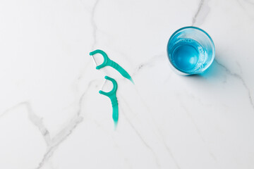 Mouthwash and floss picks on marble background