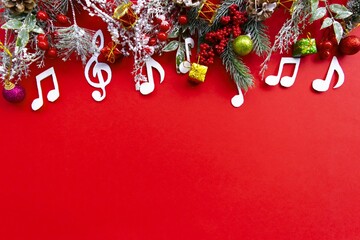 Composition with notes and christmas decorations on red background. Christmas music concept